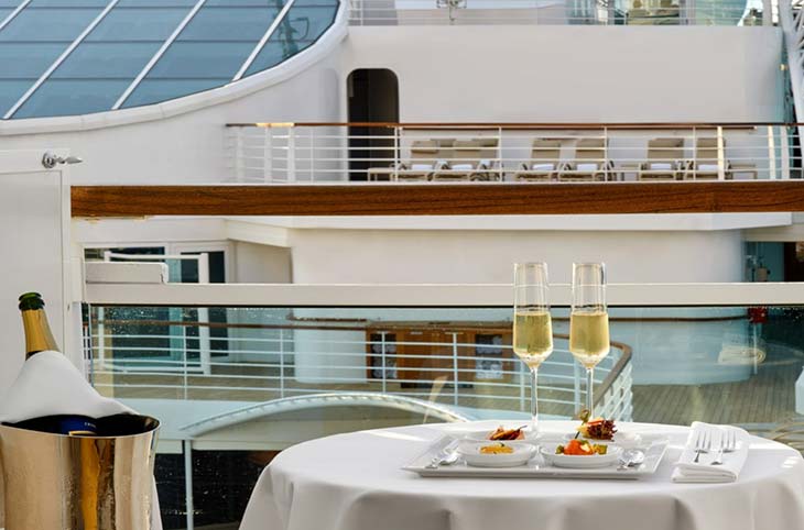 Two champagne flutes and a meal on a shipboard balcony.